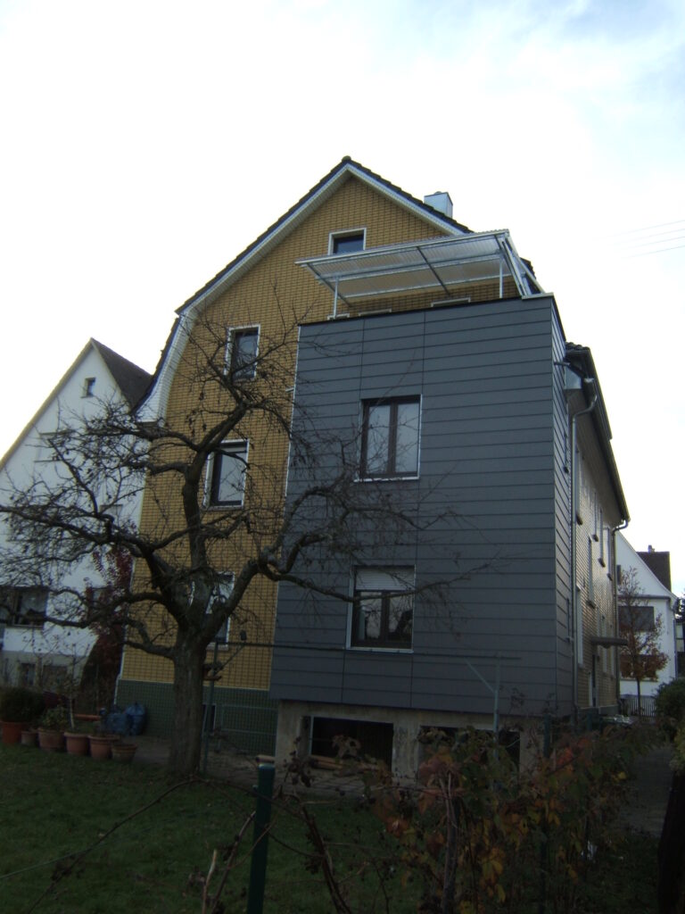 Gelbes Haus mit grauem Anbau.