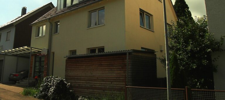 Gelbes Haus, Holzschuppen, Basketballkorb, Auto.